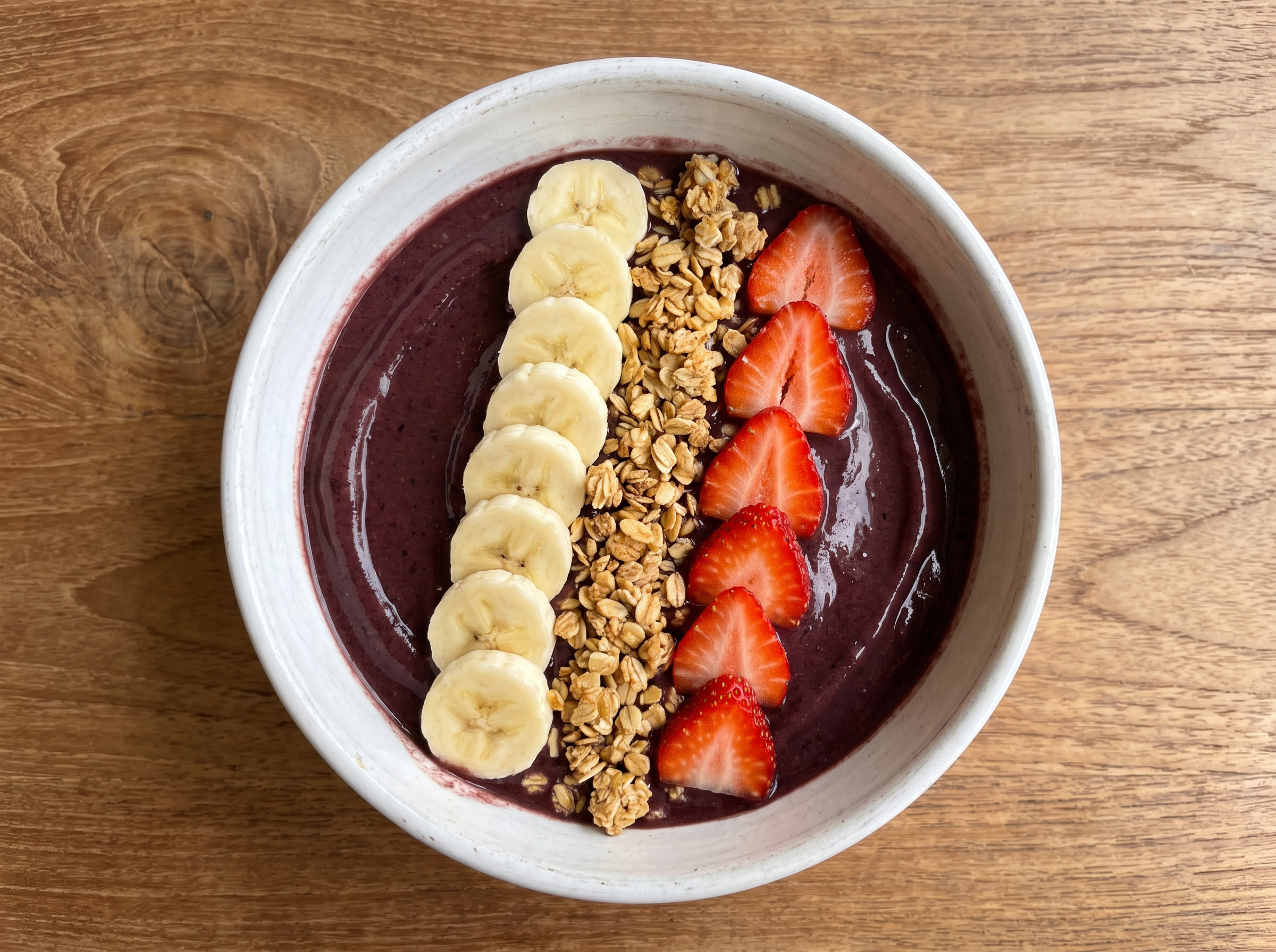 Detalhe do creme espesso de açaí com cobertura de banana, granola crocante e morango fresco