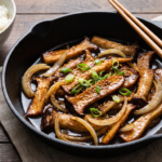 Bulgogi de cogumelos vegano dourado em frigideira de ferro, com molho agridoce brilhante, cebolinha e gergelim