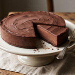 Torta gelada de chocolate escura e densa em prato de cerâmica, com uma fatia cortada mostrando o interior cremoso